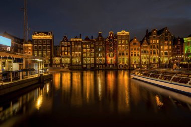 Amsterdam, Hollanda 'daki nehir kanalına yansıyan renkli ışıklı Amsterdam evlerinin panoramik görüntüsü. Mimari, seyahat arkaplanı veya duvar kağıdı