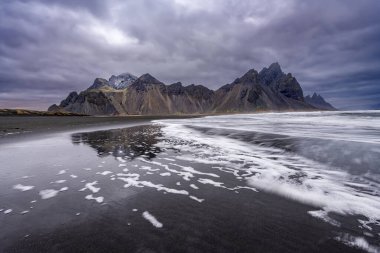 Siyah kumlu Vestrahorn Dağı 'nın panoramik manzarası ve Stoksnes, İzlanda kıyıları. Doğa, seyahat, kış arkaplanı veya duvar kağıdı
