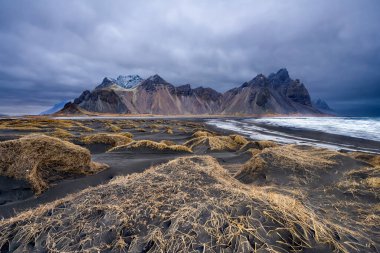 Siyah kumlu Vestrahorn Dağı 'nın panoramik manzarası ve Stoksnes, İzlanda kıyıları. Doğa, seyahat, kış arkaplanı veya duvar kağıdı