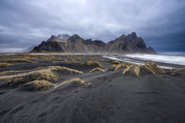Siyah kumlu Vestrahorn Dağı 'nın panoramik manzarası ve Stoksnes, İzlanda kıyıları. Doğa, seyahat, kış arkaplanı veya duvar kağıdı