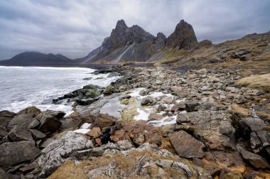 Siyah kumlu dağların panoramik manzarası ve Estrahorn, İzlanda 'da kıyı şeridi. Doğa, seyahat, kış arkaplanı veya duvar kağıdı