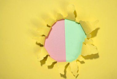 Renkli arka planı olan sarı kağıttan yırtılmış deliğin üst görüntüsü. Modelleme. Uzayı kopyala Sunum ya da şablon. Düz yatıyordu