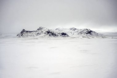İzlanda 'da karla kaplı tarlaların ve dağların manzarası. Doğa, seyahat, kış arkaplanı veya duvar kağıdı