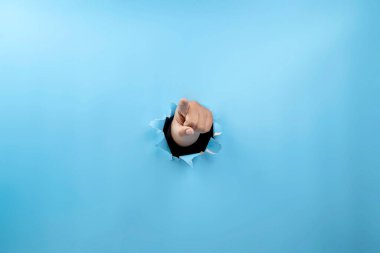 Yırtılmış kağıttan insan eli görünüyor. El işaretleri işaret ediyor. Model veya Kopyala uzayı. İşaret veya iletişim kavramı