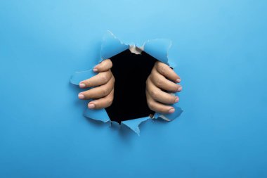 Siyah arkaplanı olan insan eli yırtılmış mavi bir kağıt. Modelleme. Uzayı kopyala Sunum veya şablon