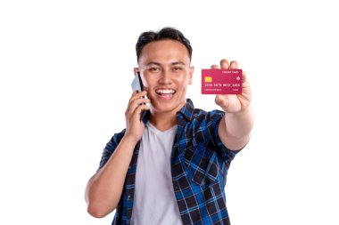 Beyaz arka planda kredi kartını gösterirken cep telefonuyla konuşan Asyalı Endonezyalı adamın portresi. Boşluğu veya maketi kopyala. Teknoloji, iletişim ya da alışveriş kavramı