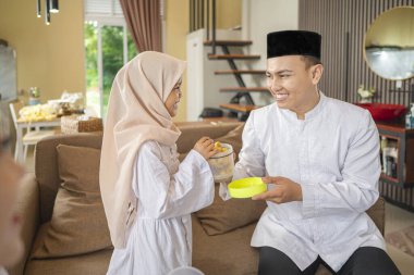 Mübarek bayramını kutlarken Endonezyalı Müslüman babanın kızıyla pasta paylaşan portresi. Mutlu Lebaran, Kurban Bayramı, İdul Fitri ve Ramazan Mübarek kutlamaları.