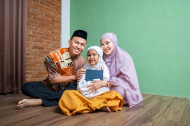 Kuran 'ı tutarken kızlarına sarılan Endonezyalı Müslüman bir ailenin portresi. İslam kutsal kitabı veya Ramazan Kareem kavramı