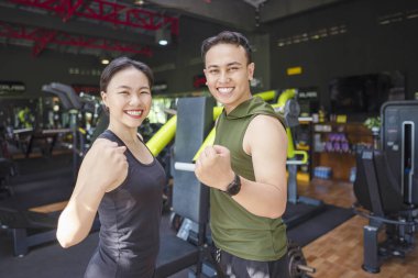 Çinli Doğu Asyalı kadın ve Endonezyalı Güneydoğu Asyalı adam spor salonunda birlikte çalışıyor. Spor salonu ve sağlıklı yaşam tarzı konsepti