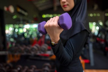 Arap Ortadoğulu Müslüman kadın spor salonunda dambıl kaldırırken spor yapıyor. Spor salonu ve sağlıklı yaşam tarzı konsepti