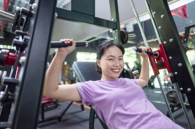 Çinli Doğu Asyalı kadın spor salonunda göğüs pres makinesi eğitimi alıyor. Spor salonu ve sağlıklı yaşam tarzı konsepti