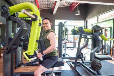 Endonezyalı güneydoğu Asyalı adam spor salonunda göğüs pres makinesi eğitimi alıyor. Spor salonu ve sağlıklı yaşam tarzı konsepti