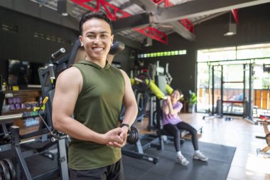 Endonezyalı güneydoğu Asyalı adam spor salonundaki eğitimden sonra kol kaslarını gösteriyor. Spor salonu ve sağlıklı yaşam tarzı konsepti