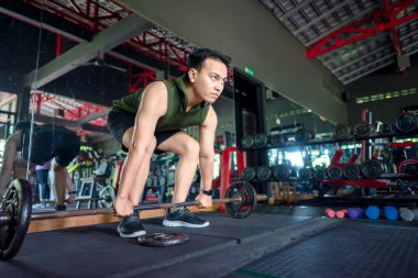 Endonezyalı güneydoğu Asyalı adam spor salonunda halter kaldırırken spor yapıyor. Spor salonu ve sağlıklı yaşam tarzı konsepti
