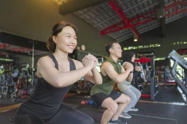 Çinli Doğu Asyalı ve Arap Ortadoğulu Müslüman kadınlar Endonezyalı güneydoğu Asyalı erkeklerle spor salonunda yoga sınıfında antrenman yapıyor ve esniyorlar. Spor salonu ve sağlıklı yaşam tarzı konsepti