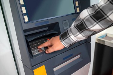 Banka hizmetine erişmek ya da para çekmek için ATM 'ye (otomatik para makinesi) bir PIN yerleştiren bir erkek. Teknoloji, finans ve bankacılık kavramı