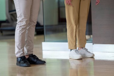 Modern ofis binasında ahşap zemini olan bir grup iş adamı yan yana duruyor. İş, takım çalışması, işbirliği ve profesyonel katılım kavramı