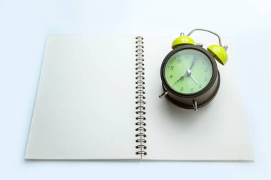 Beyaz arka planda yeşil alarm saati ve defter. Model ya da kopyalama alanı için boş alan. Eğitim ya da öğrenim kavramı