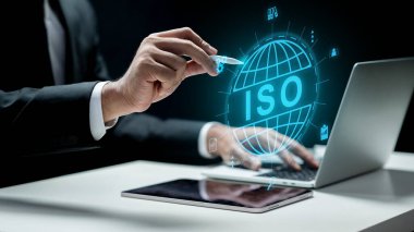 Bilgisayarlı bir iş adamı tablet ekranında ISO metni olan bir dünyanın simgesine dokunuyor. Sanal ekranda teknolojik yenilik. ISO sertifikası, küresel standartlar ve kalite güvencesi kavramı