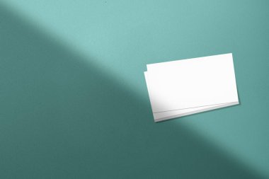 Cyan arka planda gölgesi olan bir yığın kartvizitin üst görüntüsü. Boş kağıt ya da yaprak. Tasarımınız için boşluk oluştur veya kopyala