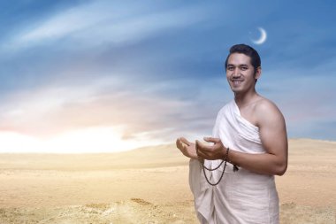 Endonezyalı güneydoğu Asyalı Müslüman beyaz geleneksel kıyafetler ya da ihram giyen adam elini kaldırıyor ve hac için dua ederken dua ediyor. Hac veya umrah kavramı