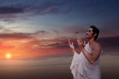 Endonezyalı güneydoğu Asyalı geleneksel beyaz kıyafetler giyen Müslüman adam elini kaldırarak hacca dua ediyor. Hac veya umrah kavramı