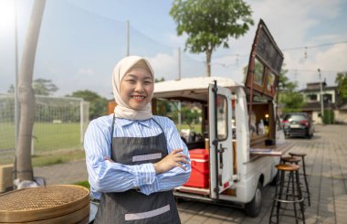 Endonezyalı güneydoğu Asya 'lı Çinli tesettürlü, tesettürlü, Müslüman kadın kahveci kahve dükkanının önünde duruyor. Kamyon üzerinde küçük bir kafe ya da kafe işletmesi