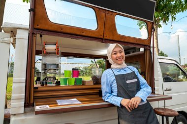 Endonezyalı güneydoğu Asya 'lı Çinli tesettürlü, tesettürlü, Müslüman kadın kahveci kahve dükkanının önünde duruyor. Kamyon üzerinde küçük bir kafe ya da kafe işletmesi