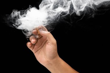 Sigara içen ve siyah arka planı olan bir duman bulutu salan bir adam. Hayır ya da sigarayı bırakmak, kötü bir alışkanlık ve sağlıksız.