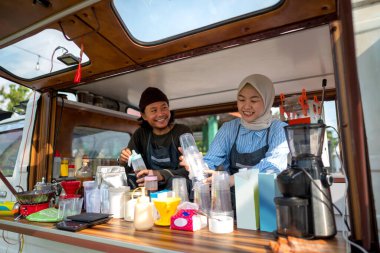 Endonezyalı güneydoğu Asyalı erkek ve tesettürlü Çinli Müslüman bir kadın siparişi vermeden önce kafeteryalarını hazırlıyorlar. Kamyon üzerinde küçük bir kafe ya da kafe işletmesi