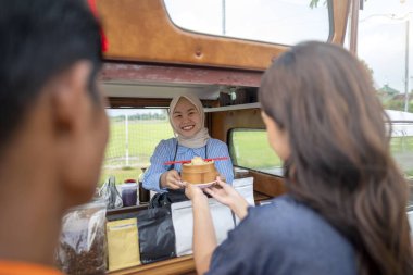 Endonezya 'nın güneydoğusunda Çinli Müslüman kadın garson müşterilere yemek servisi yapıyor. Kamyonda küçük bir işletme.