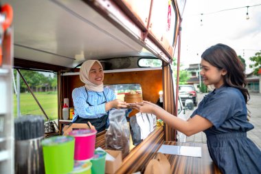 Endonezya 'nın güneydoğusunda Çinli Müslüman kadın garson müşterilere yemek servisi yapıyor. Kamyonda küçük bir işletme.