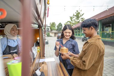 Endonezya 'nın güneydoğusunda Çinli Müslüman kadın garson müşterilere yemek servisi yapıyor. Kamyonda küçük bir işletme.
