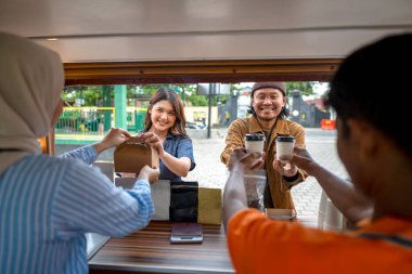 Endonezyalı güneydoğu Asyalı erkek ve tesettürlü Çinli Müslüman kadın müşterilere içki ve atıştırmalık servisi yapıyorlar. Kamyon üzerinde küçük bir kafe ya da kafe işletmesi