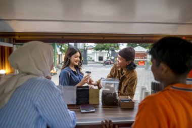 Endonezyalı güneydoğu Asyalı erkek ve tesettürlü Çinli Müslüman kadın müşterilere içki ve atıştırmalık servisi yapıyorlar. Kamyon üzerinde küçük bir kafe ya da kafe işletmesi