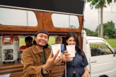 Endonezyalı güneydoğu Asyalı çift kahve dükkanının önünde kahve içiyor. Kamyon üzerinde küçük bir kafe ya da kafe işletmesi