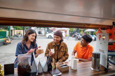 Endonezyalı güneydoğu Asyalı kadın dükkanın önünde yemek yemekten zevk alıyor. Kamyonda küçük bir işletme.