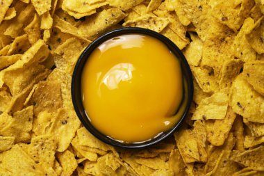 Siyah kasede peynir soslu nachos tortilla cipsinin yakın görüntüsü. Yiyecek ve atıştırmalık konsepti