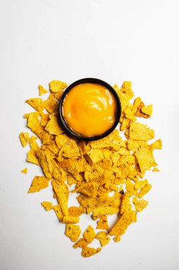Beyaz arka planda siyah kasede peynir soslu Nachos tortilla cipsi. Yiyecek ve atıştırmalık konsepti