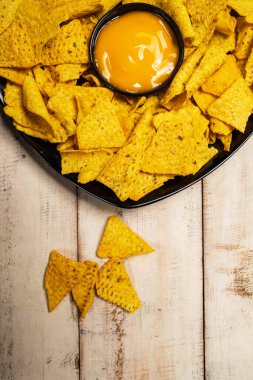 Masadaki peynir soslu siyah tabakta Nachos tortilla cipsi. Uzayı kopyala Yiyecek ve atıştırmalık konsepti