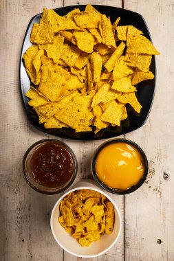 Peynirli nachos tortilla cipsi ve masada salsa barbekü sosu. Yiyecek ve atıştırmalık konsepti