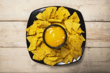 Masadaki peynir soslu siyah tabakta Nachos tortilla cipsi. Yiyecek ve atıştırmalık konsepti