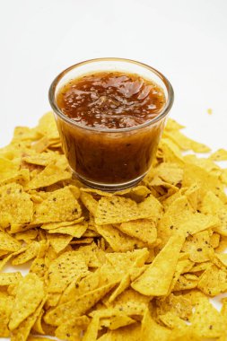 Beyaz arka planda cam bir kasede salsa soslu nachos tortilla cipsi. Yiyecek ve atıştırmalık konsepti