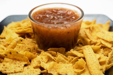 Siyah tabakta Nachos tortilla cipsi ve beyaz arka planda salsa barbekü sosu. Yiyecek ve atıştırmalık konsepti