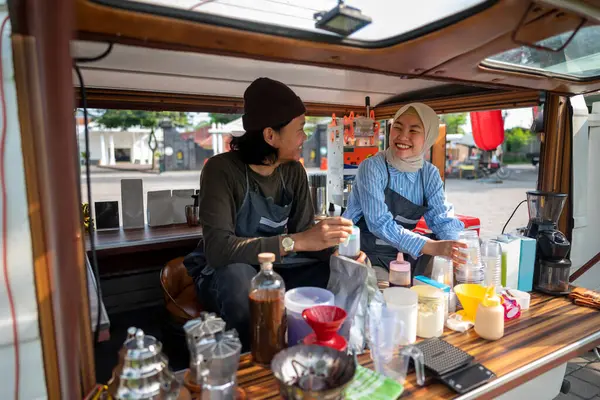 Endonezyalı güneydoğu Asyalı erkek ve tesettürlü Çinli Müslüman bir kadın siparişi vermeden önce kafeteryalarını hazırlıyorlar. Kamyon üzerinde küçük bir kafe ya da kafe işletmesi