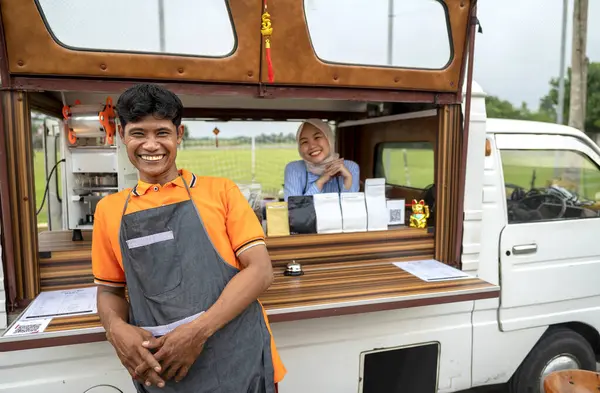 Endonezyalı güneydoğu Asyalı bir erkek ve kafeteryalarına güvenen tesettürlü Çinli Müslüman bir kadın. Kamyon üzerinde küçük bir kafe ya da kafe işletmesi