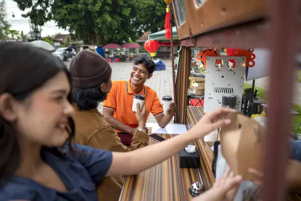 Kadın garson Endonezyalı Güneydoğu Asyalı müşterilere yemek servisi yapıyor. Kamyonda küçük bir işletme.