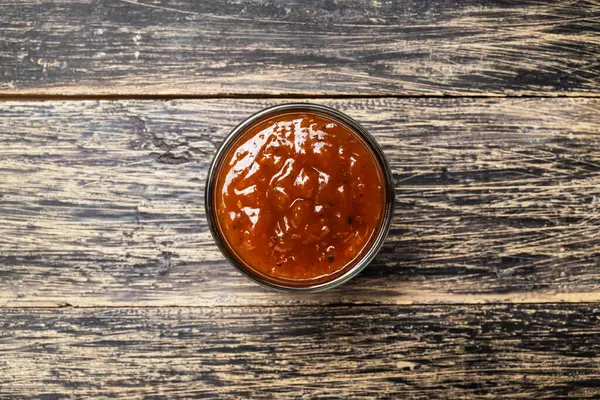 Ahşap bir masanın üzerindeki kasedeki lezzetli salsa barbekü sosunun yakın görüntüsü. Üst görünüm