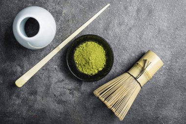 Siyah kasede kibrit yeşil çay tozu ve siyah bir masada kaşık ile geleneksel bambu fırçası çırpışı. Uyuşan yeşil çay yapmak için aksesuarlar. Üst görünüm