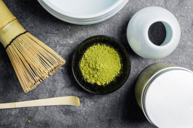 Siyah kasede kibrit yeşil çay tozu ve siyah bir masada boş bir kase ve kaşık ile geleneksel bambu fırçası çırpışı. Uyuşan yeşil çay yapmak için aksesuarlar. Üst görünüm